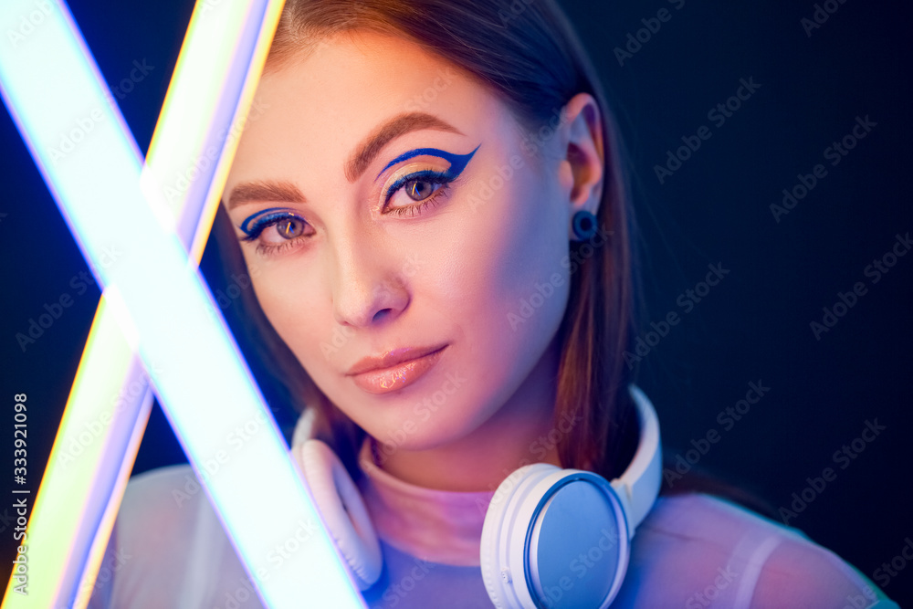 Toned portrait of beautiful woman with neon lamps on dark background