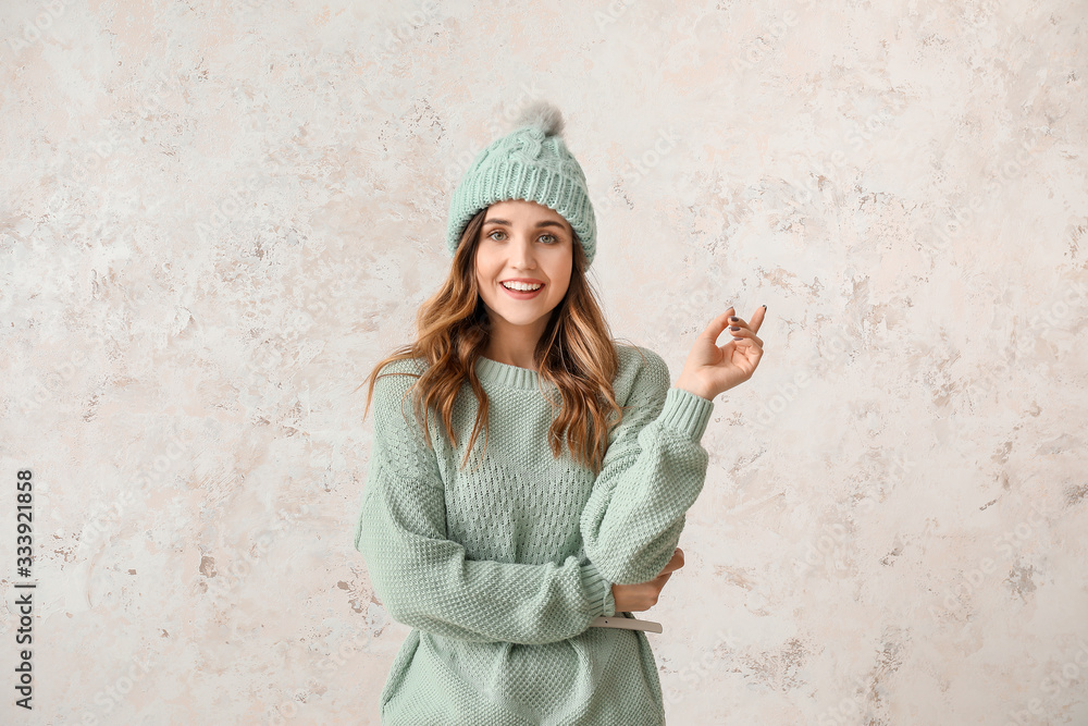 Young woman in warm sweater on light background