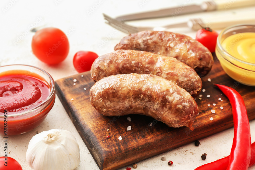 Board with tasty grilled sausages and sauces on table