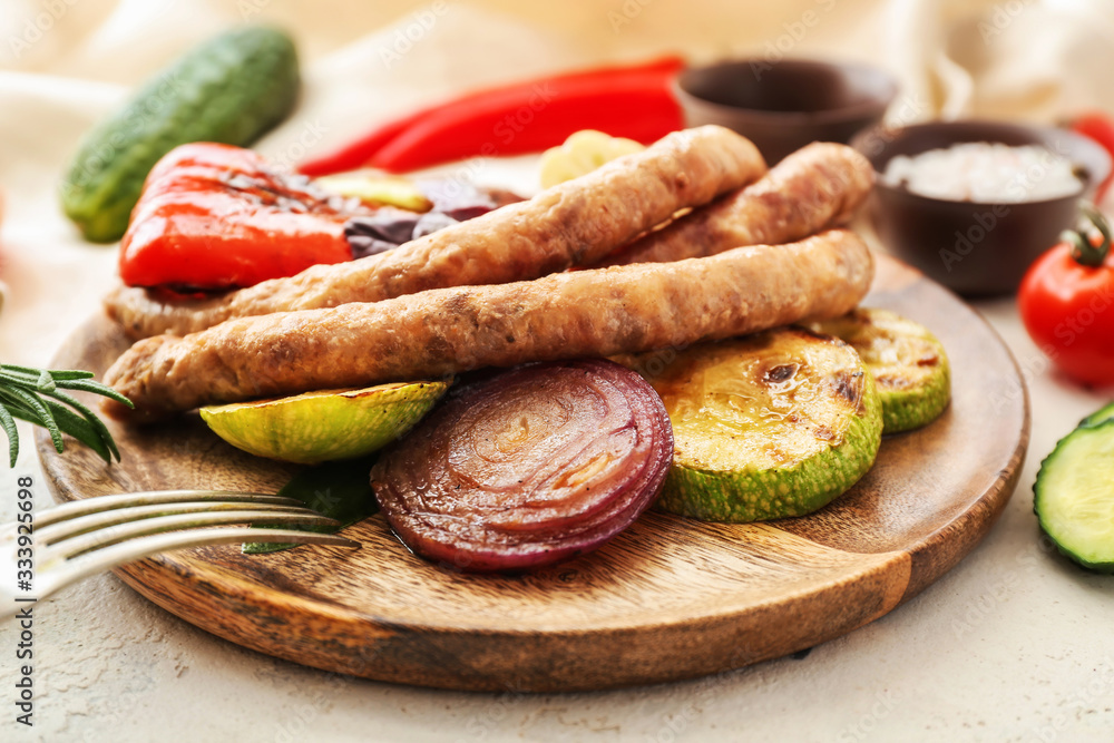 Plate with tasty grilled sausages and vegetables on table