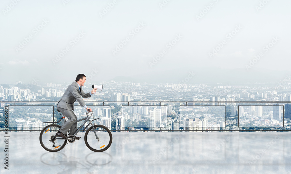 Businessman with megaphone in hand on bike