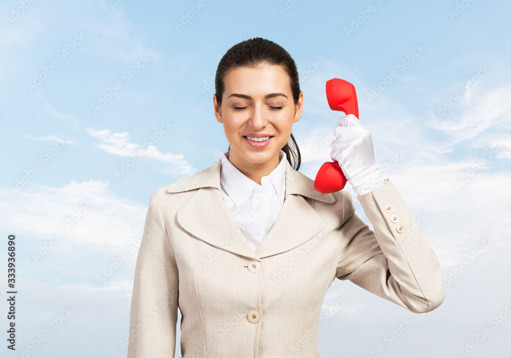 Young business woman holding red retro phone