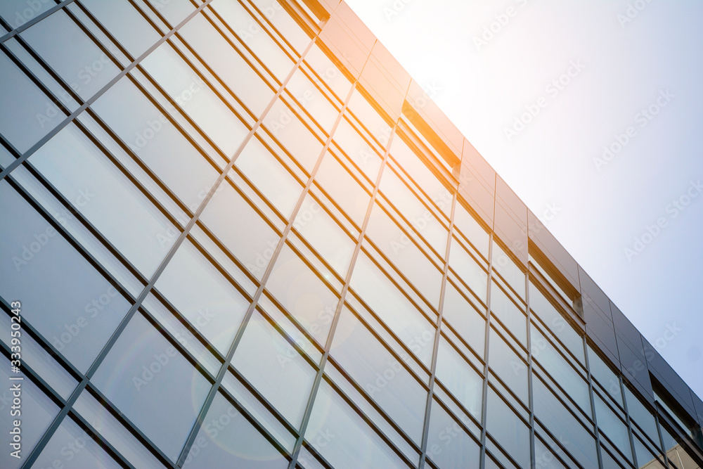 Facade of modern glass building at sunset. Warm and cool tone contrast. Sun flare.