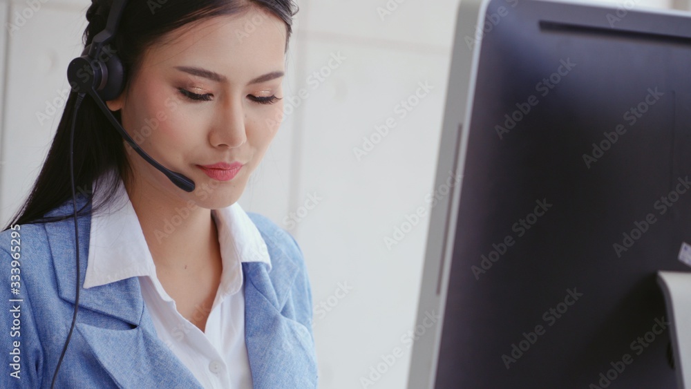 Customer support agent or call center with headset works on desktop computer while supporting the cu