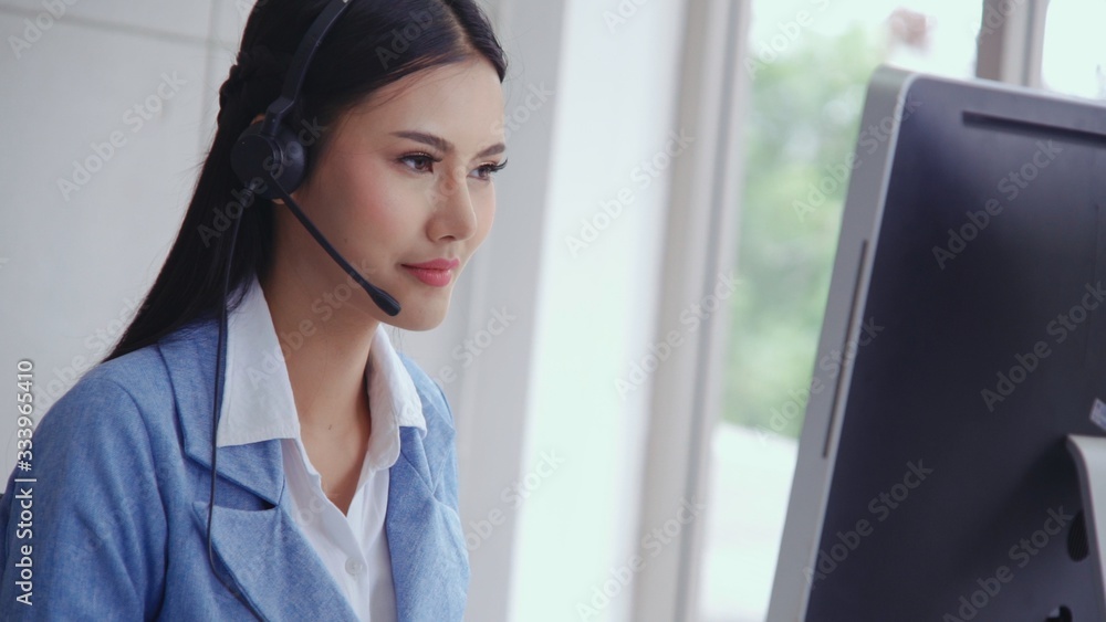 Customer support agent or call center with headset works on desktop computer while supporting the cu