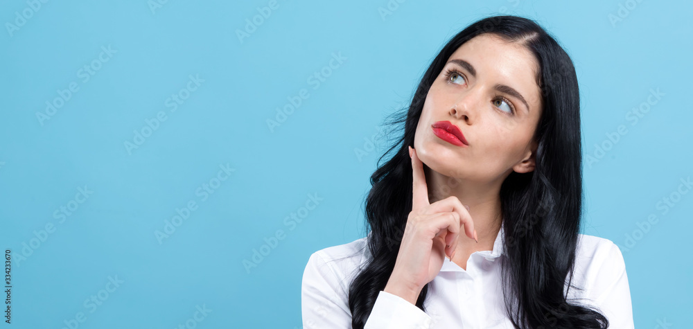 Young woman in a thoughtful pose on a blue background