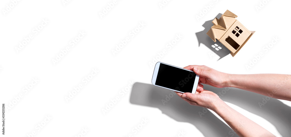 Person using a smartphone with a miniature house from above