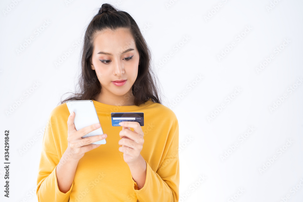 Young beauty Asian woman shopping payment online with credit card on smartphone and she wearing a ye