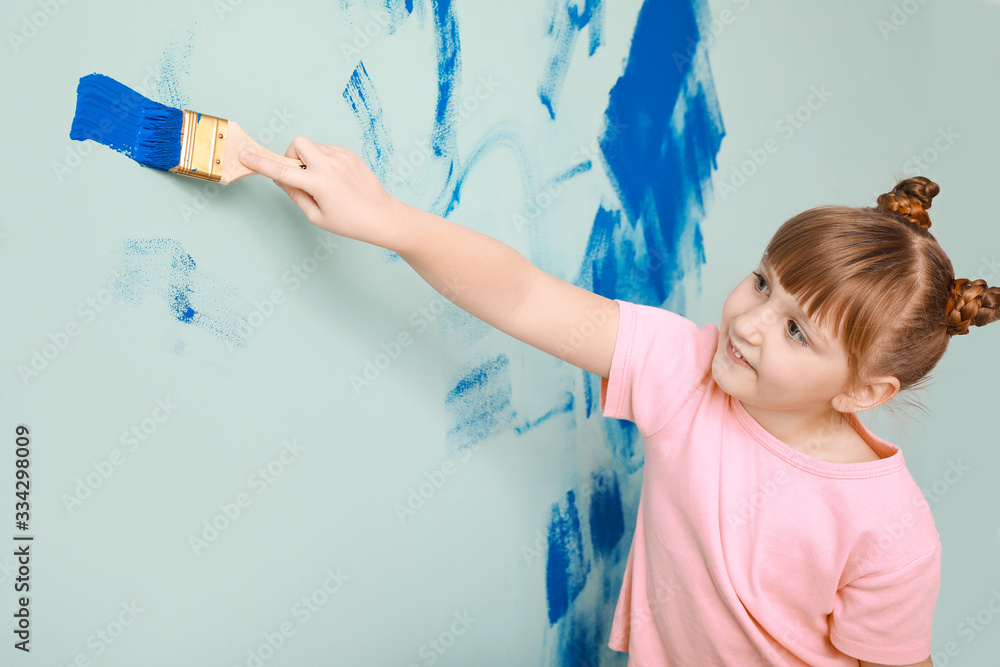 Little girl painting wall in room