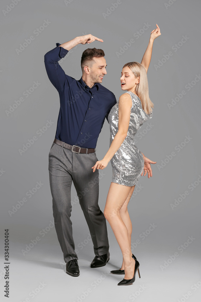 Happy dancing young couple on grey background