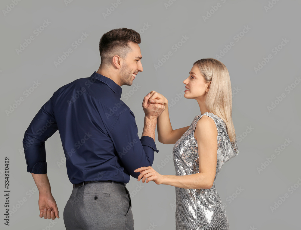 Happy dancing young couple on grey background