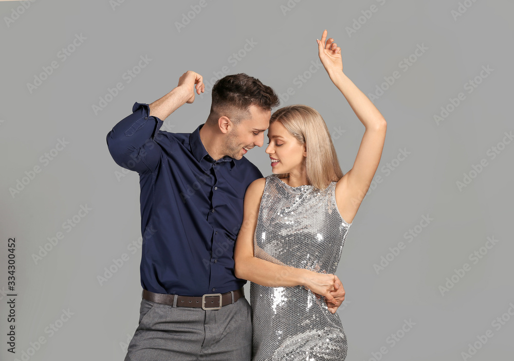 Happy dancing young couple on grey background