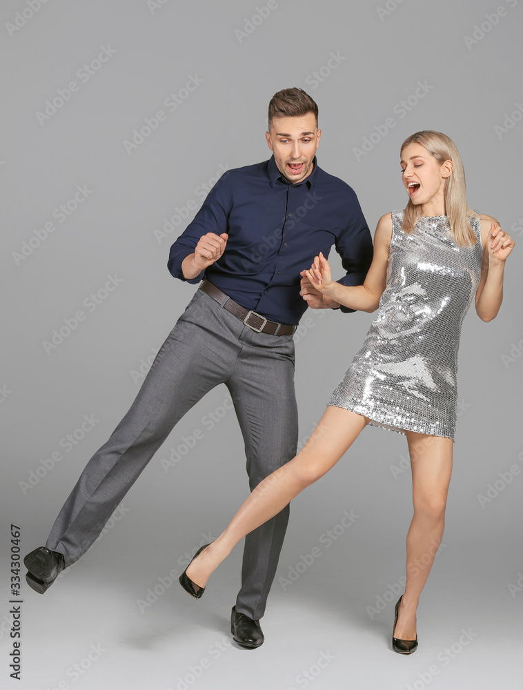 Happy dancing young couple on grey background