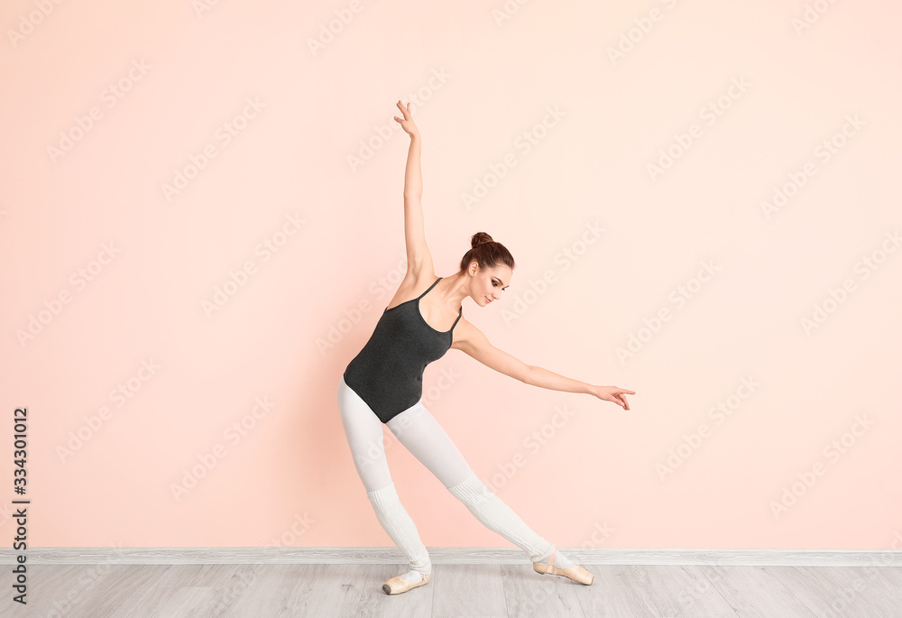 Beautiful young ballerina near color wall