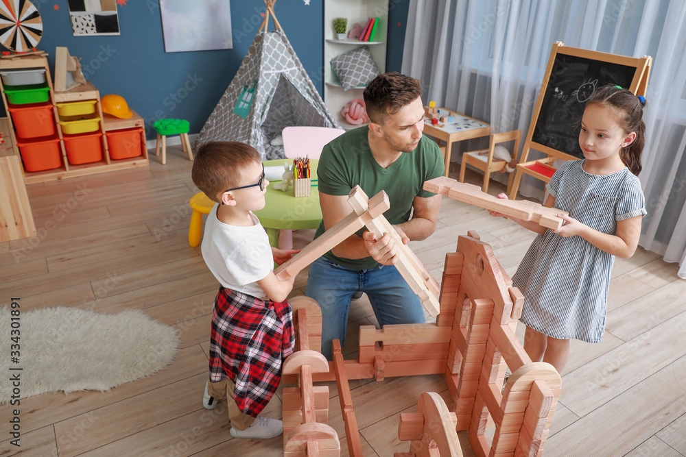 Father and little children playing with take-apart house at home