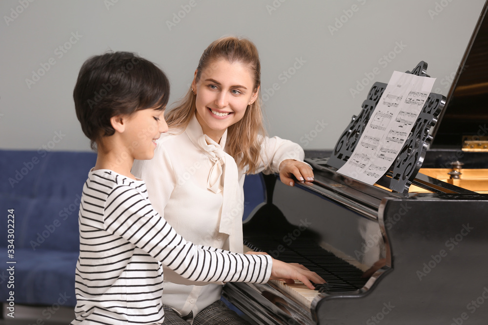 Private music teacher giving piano lessons to little boy