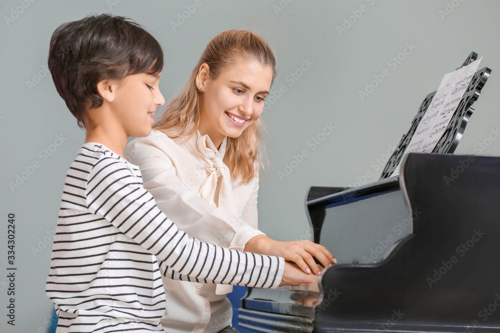 Private music teacher giving piano lessons to little boy