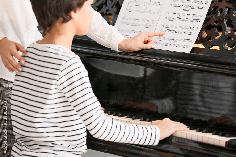 Private music teacher giving piano lessons to little boy