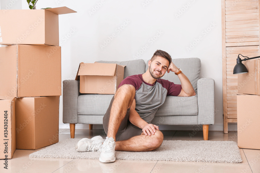 Young man with moving boxes in his new home