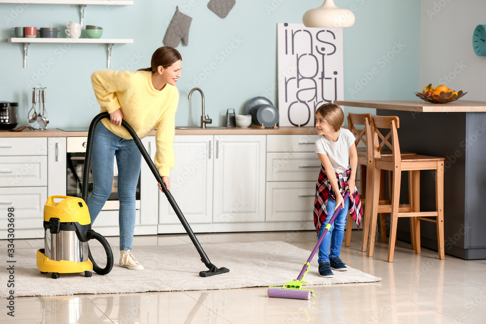 Young woman with her little daughter cleaning kitchen