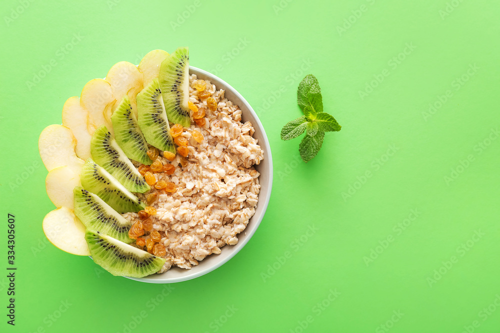 Bowl with tasty sweet oatmeal on color background