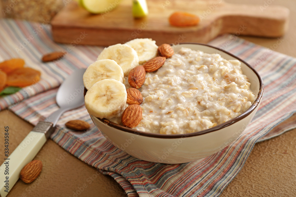 Bowl with tasty sweet oatmeal on table