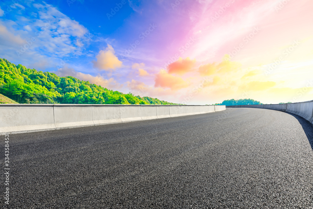 Empty asphalt road and green tea plantation nature landscape at sunset.