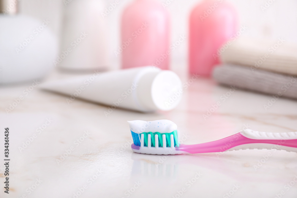 Tooth brush with paste on table in bathroom