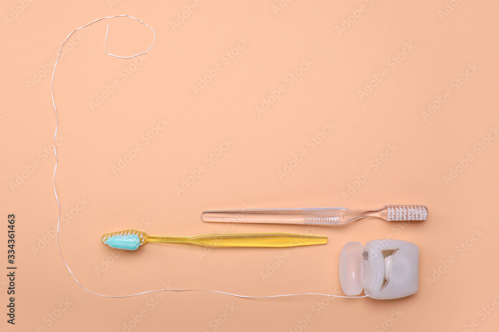 Tooth brushes with paste and dental floss on color background