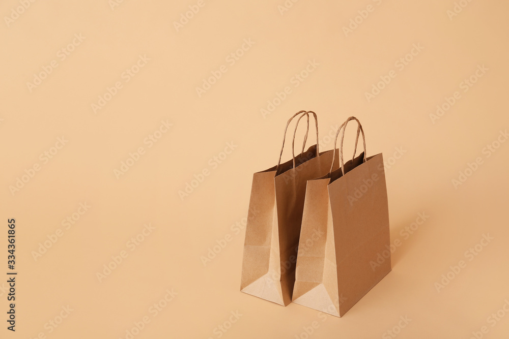 Paper shopping bags on color background