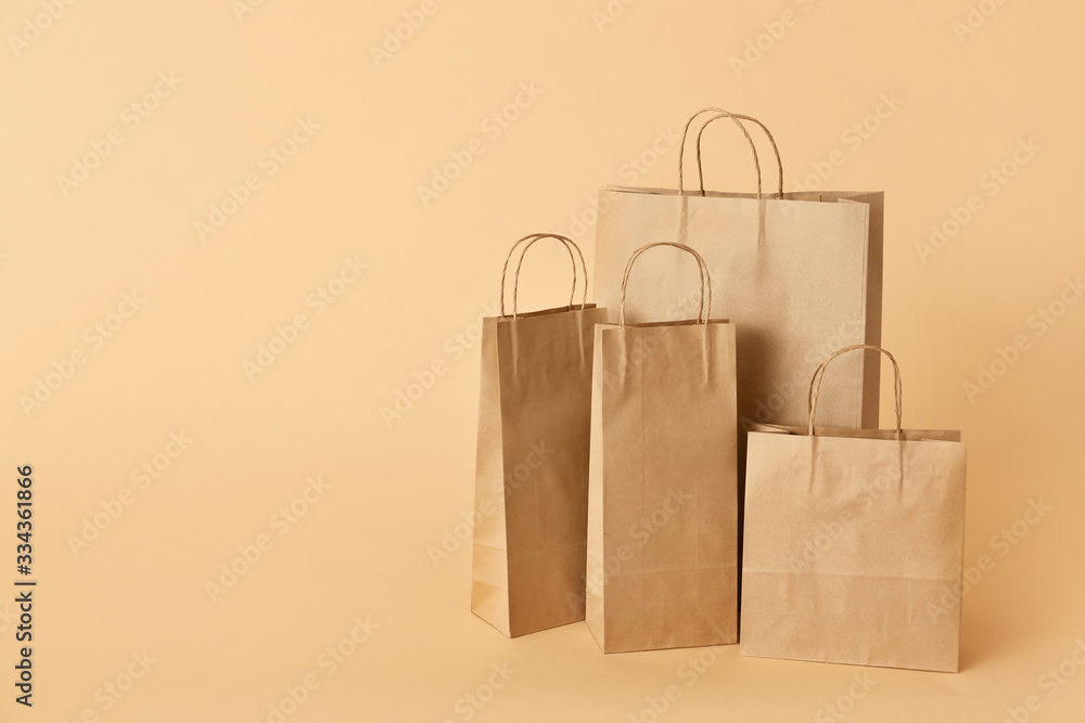 Paper shopping bags on color background