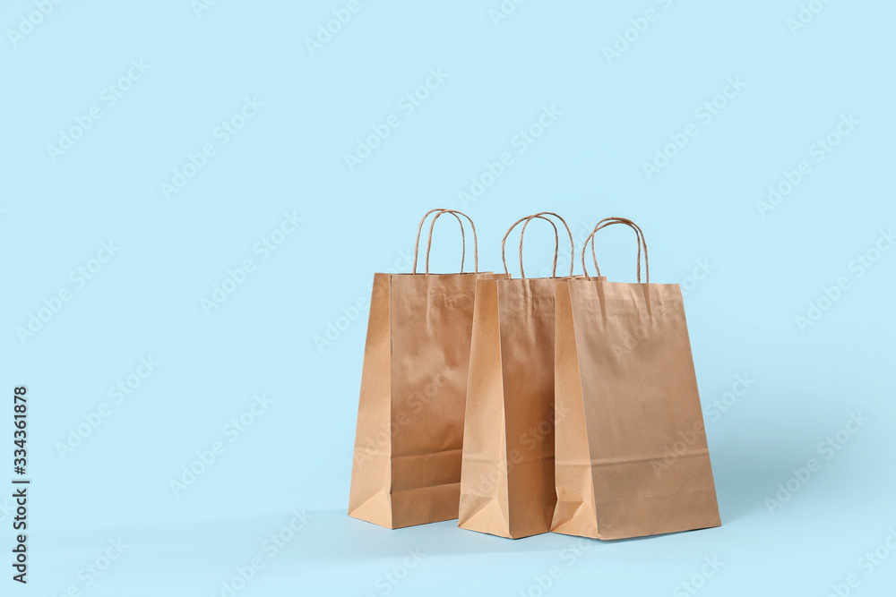 Paper shopping bags on color background