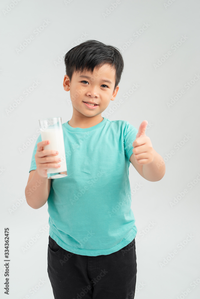 Cute kid drinking milk and showing thumb up sign, isolated on white background