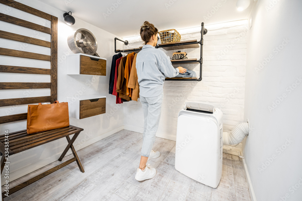 Young woman choosing clothes in the modern small wardrobe at home