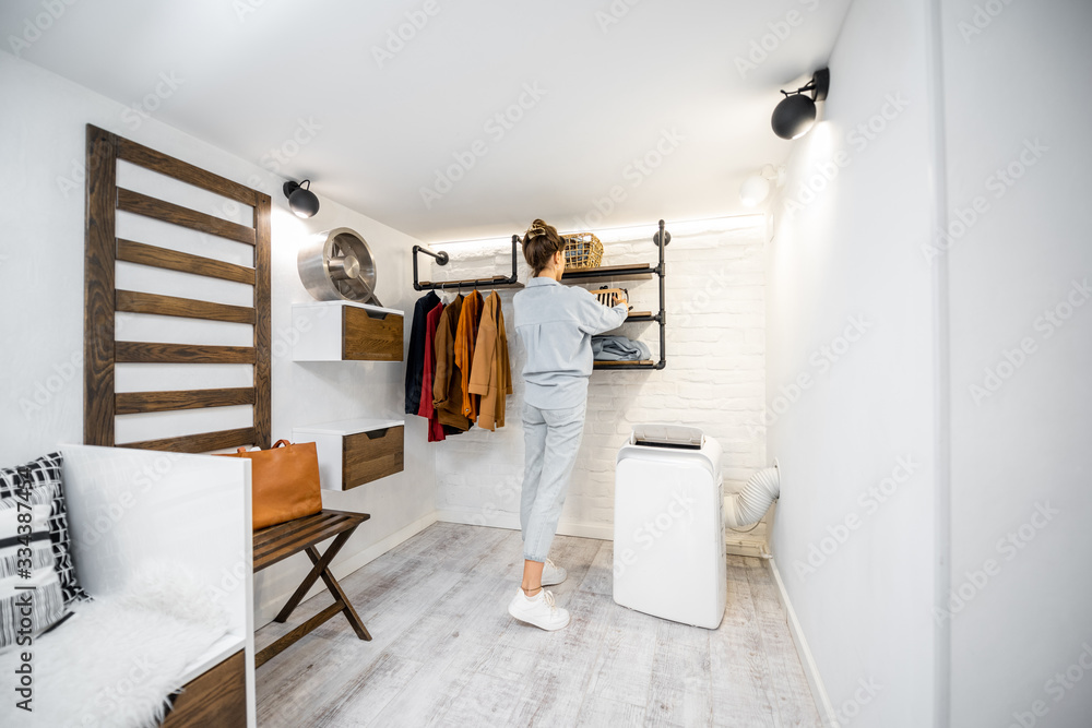 Young woman choosing clothes in the modern small wardrobe at home