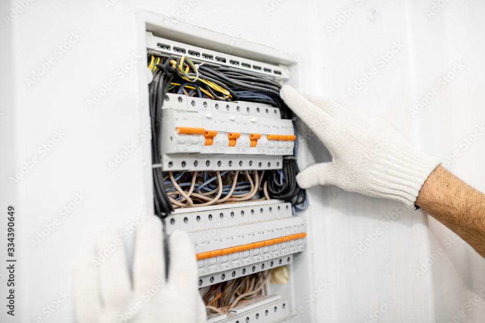 Electrician installing or repairing apartment electrical panel, close-up view