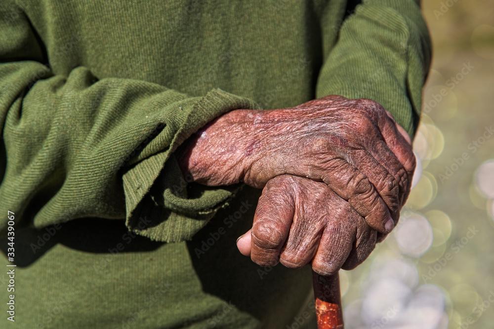 Old mans hands holding a cane