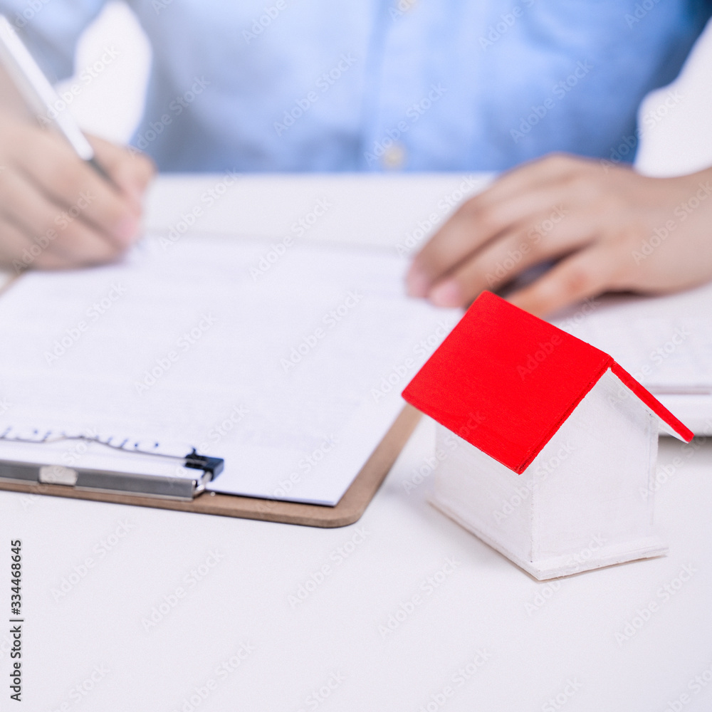 Business concept - Young Asian man in blue shirt calculates, signs agreement contract to buy a house