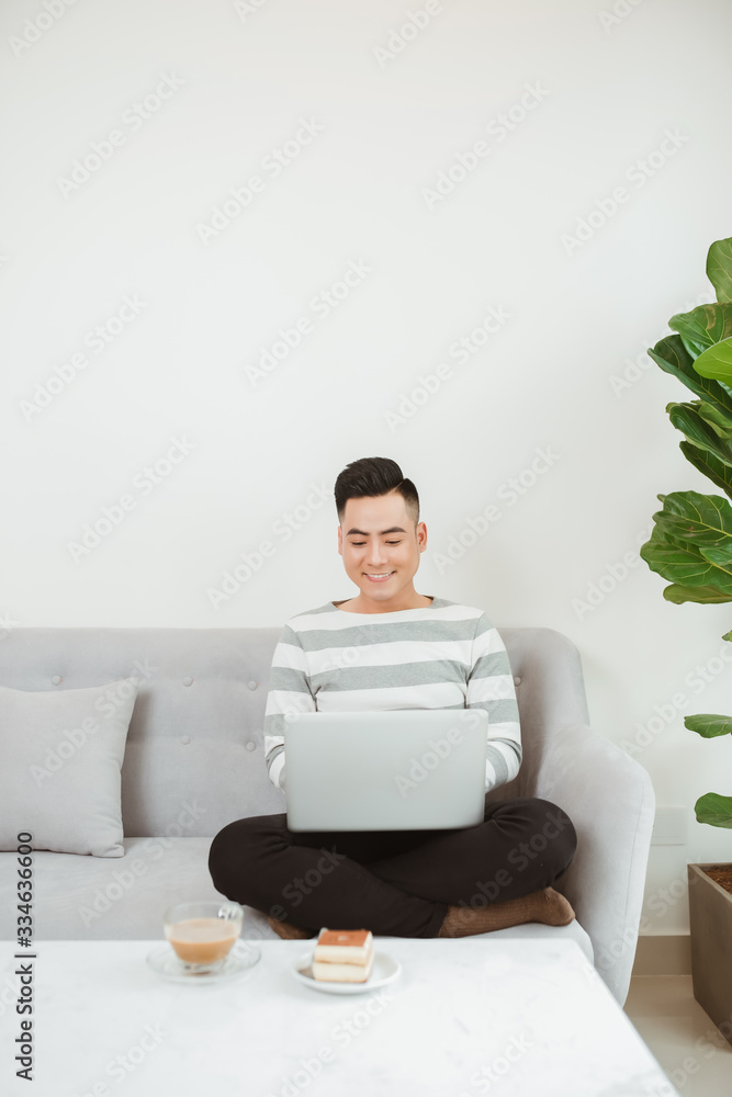 Young man using latop when sitting on sofa