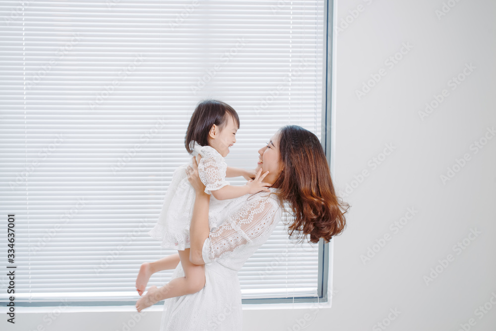 慈爱的妈妈在家里和女儿一起玩，把她举到空中