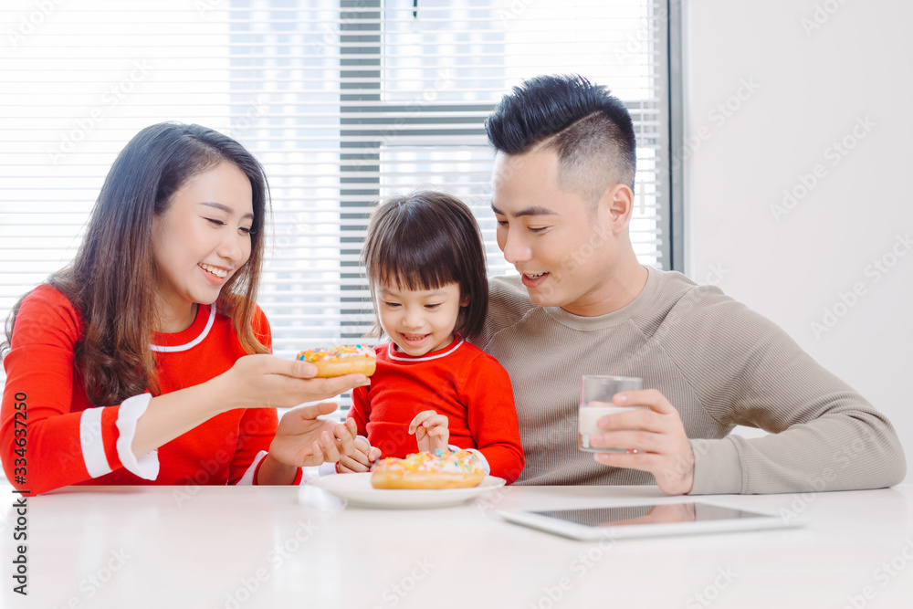 快乐的年轻家庭，孩子们在阳光明媚的白色餐厅享用早餐