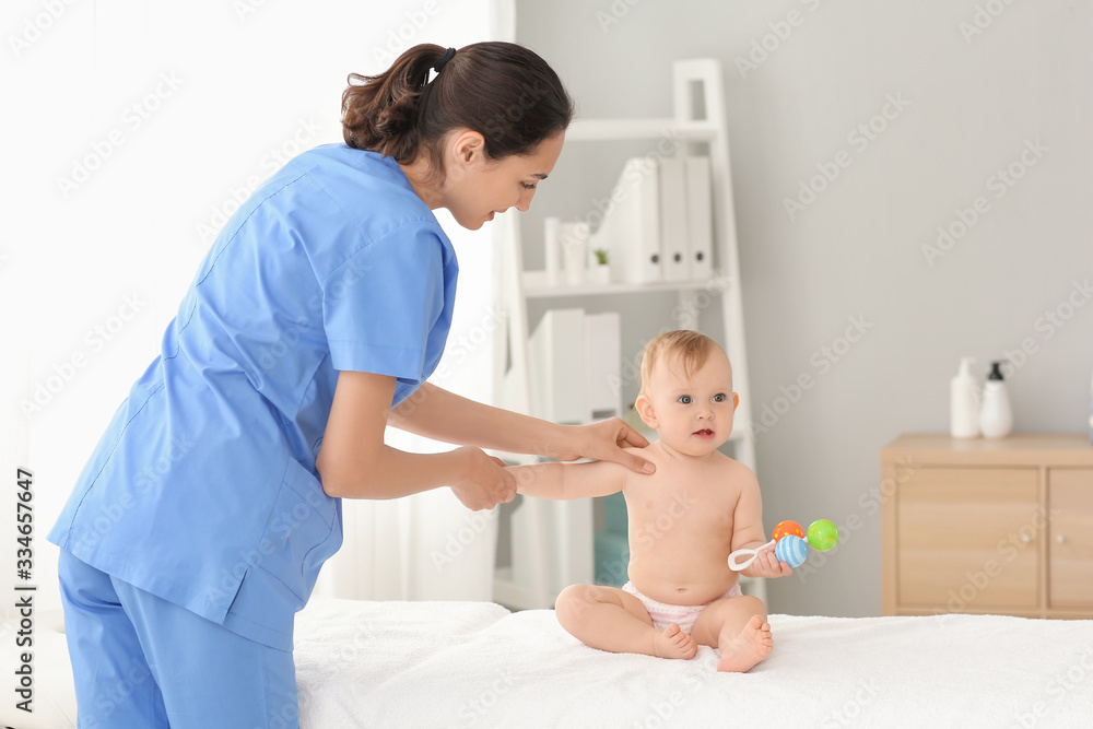 Massage therapist working with cute baby in medical center