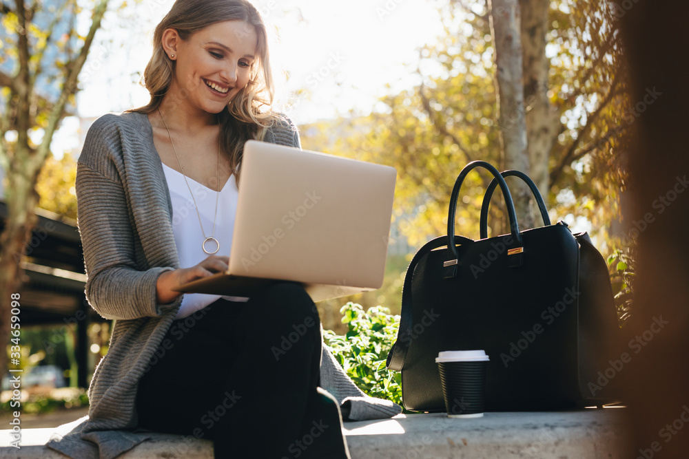 Businesswoman sitting outside using laptop