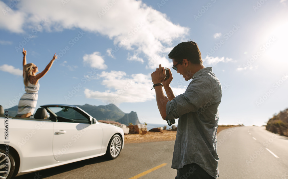 Man photographing his girlfriend in a cabriolet