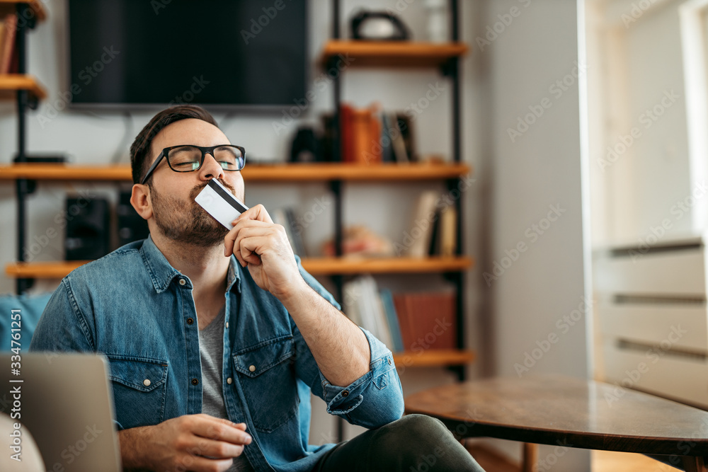 Portrait of a man kissing credit card, at home.