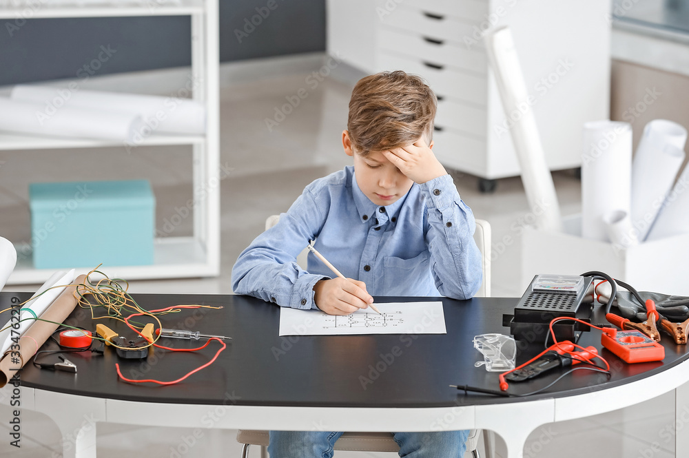 Cute little electrician performing wiring at table