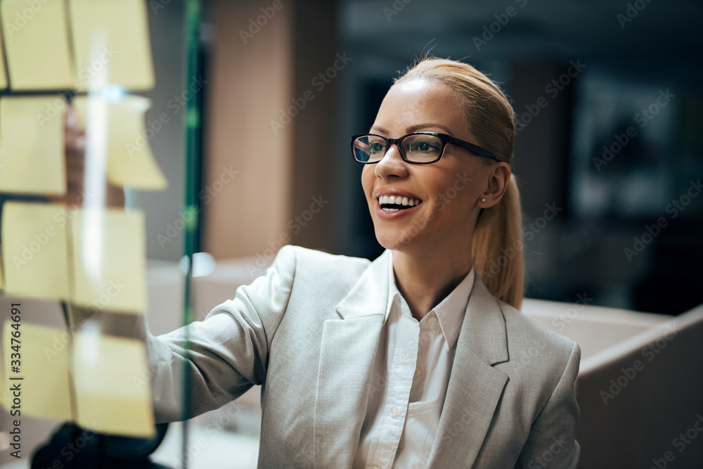 一位微笑的金发女商人的特写肖像，她在做笔记。