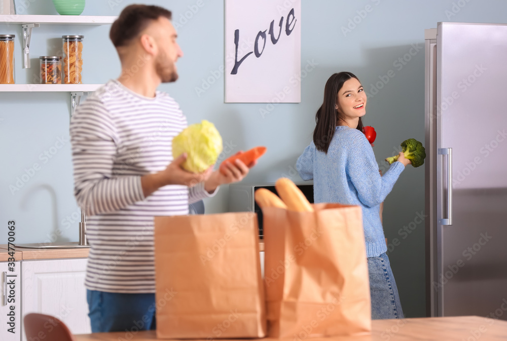 Young couple unpacking fresh products from market in kitchen