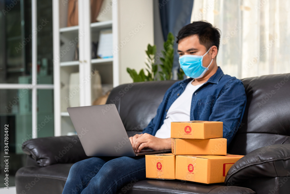 Asian man working laptop computer from home on the sofa with postal parcel, Online sales ideas Work 