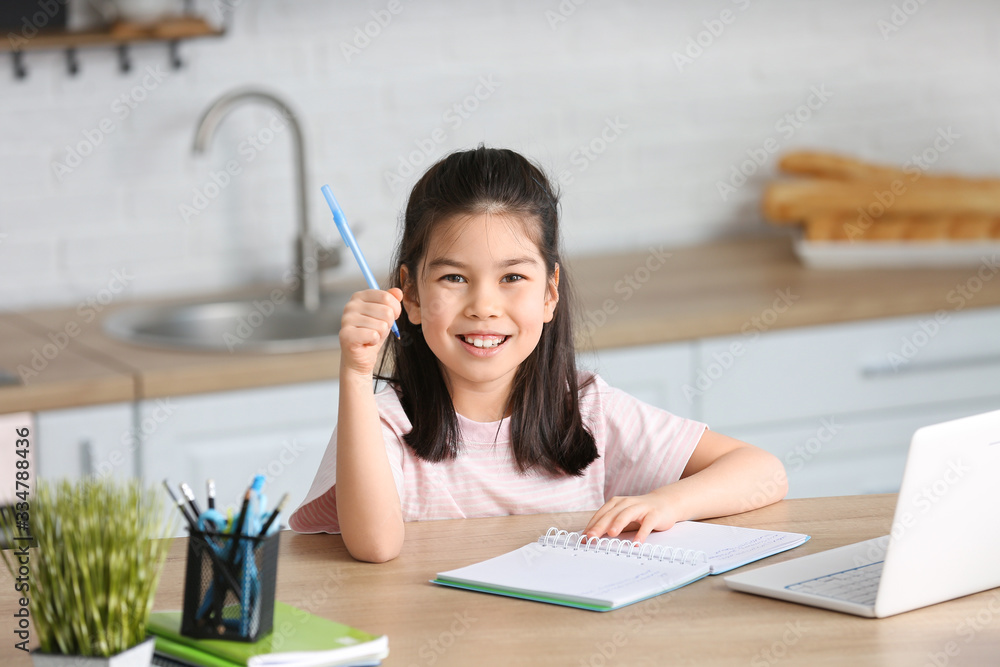 Little Asian girl doing lessons at home